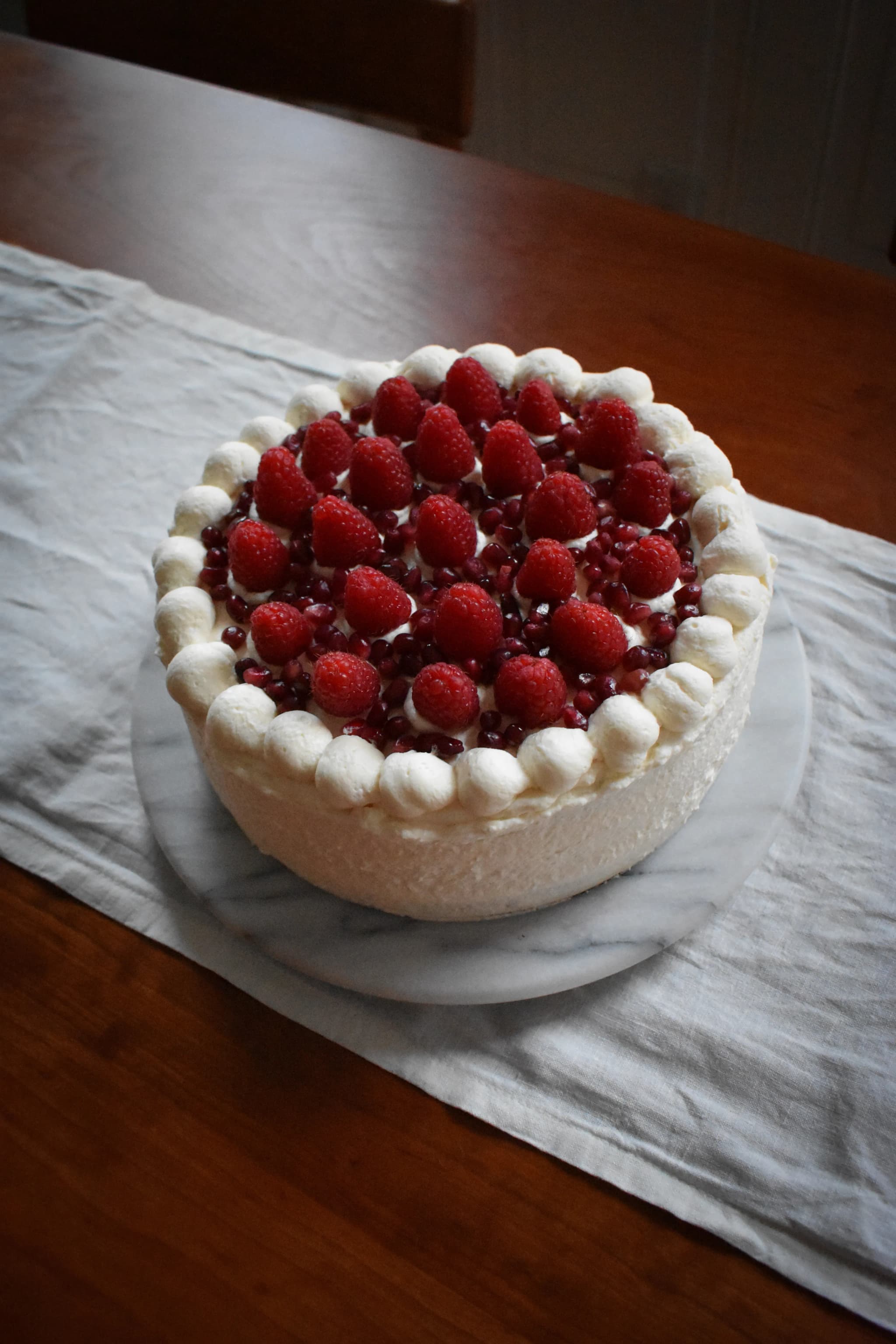 vanilla cake topped with raspberries and pomagranate seeds